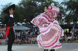 A couple dressed in traditional Mexican costumes dance on stage in the Sayulita plaza