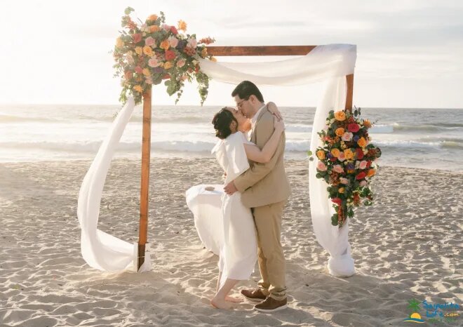 Couple kissing under a floral arch on the beach at a Sayulita destination wedding